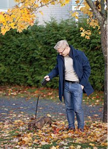 Henri ulkoilee koiransa kanssa syksyisten lehtien peittämällä kadulla.