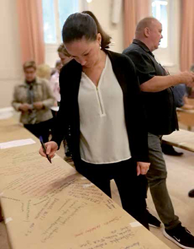 Toiminnanjohtaja Milja Karjalainen kynä kädessä tekemässä merkintään paperille.