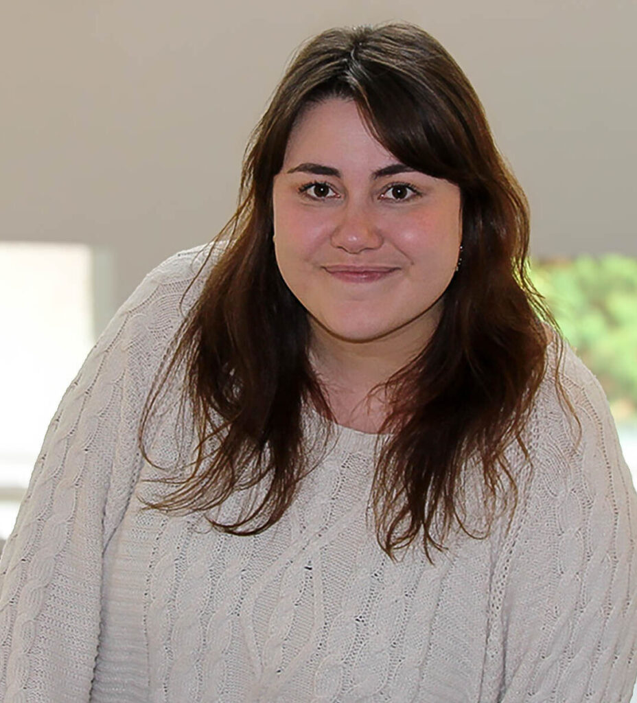 Vaaleassa villapaidassa hymyilevä, pitkät tummat hiukset