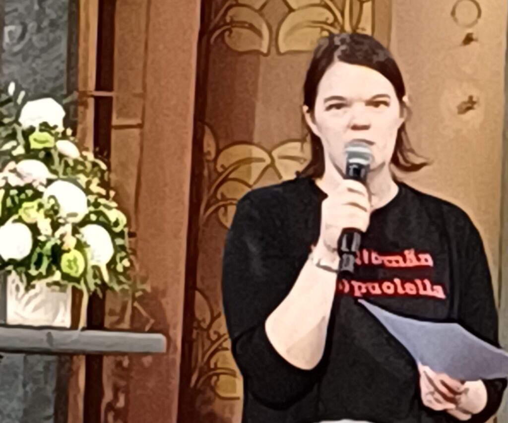 Tummatukkainen nainen puhumassa mikrofoniin