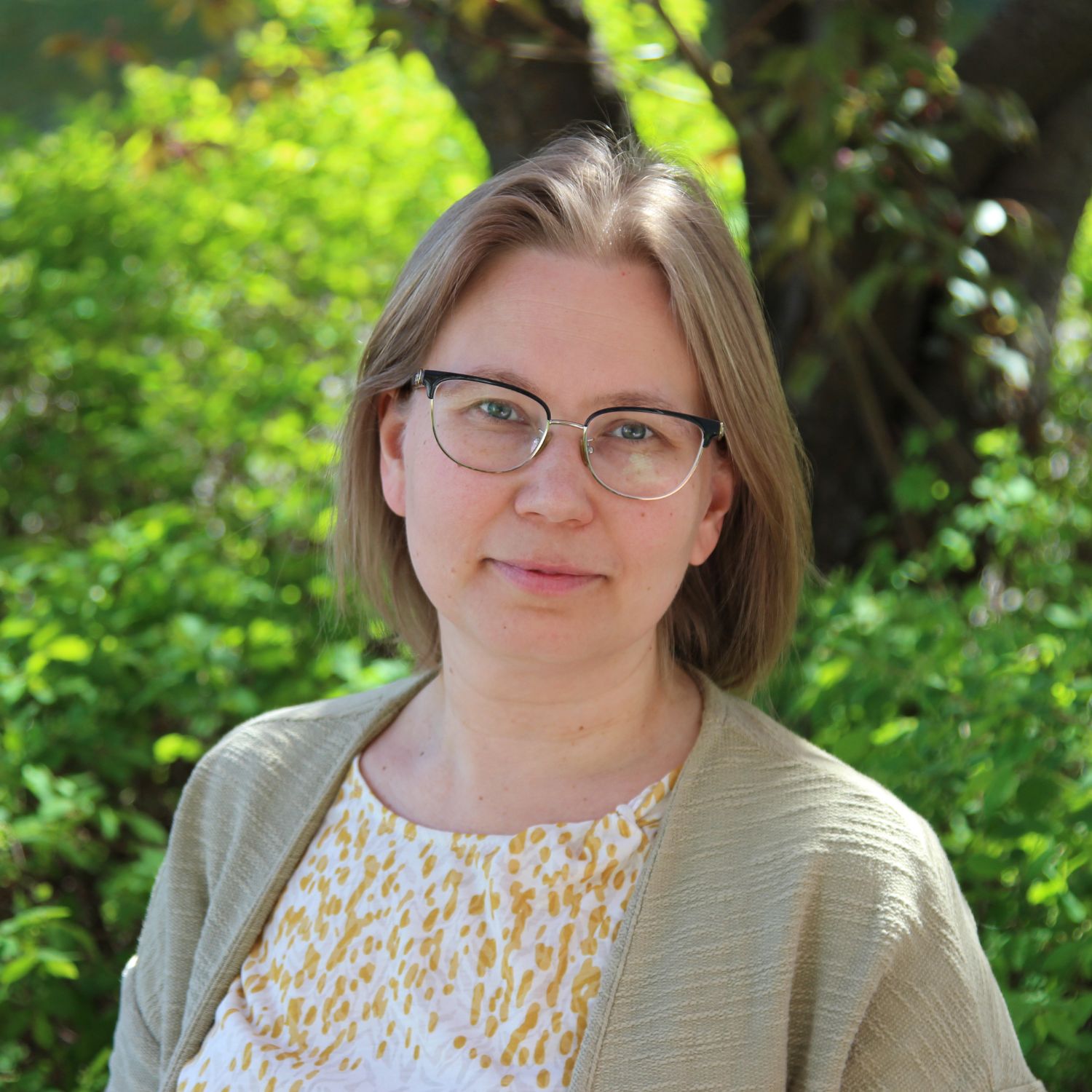 Vaalea silmälasipäinen ja polkkatukkainen nainen vihreässä puisto kesällä.