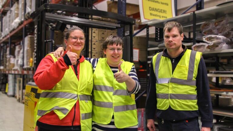 Kolme ihmistä hymyilemässä ja näyttämässä peukkua suojaliivit päällä.