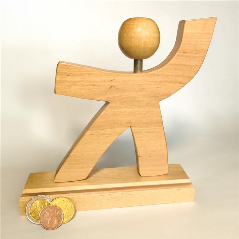 Vatesin puinen logo, jossa hahmon vasen käsi on kohti taivasta. Kuvan vasemmassa reunassa kolikoita.