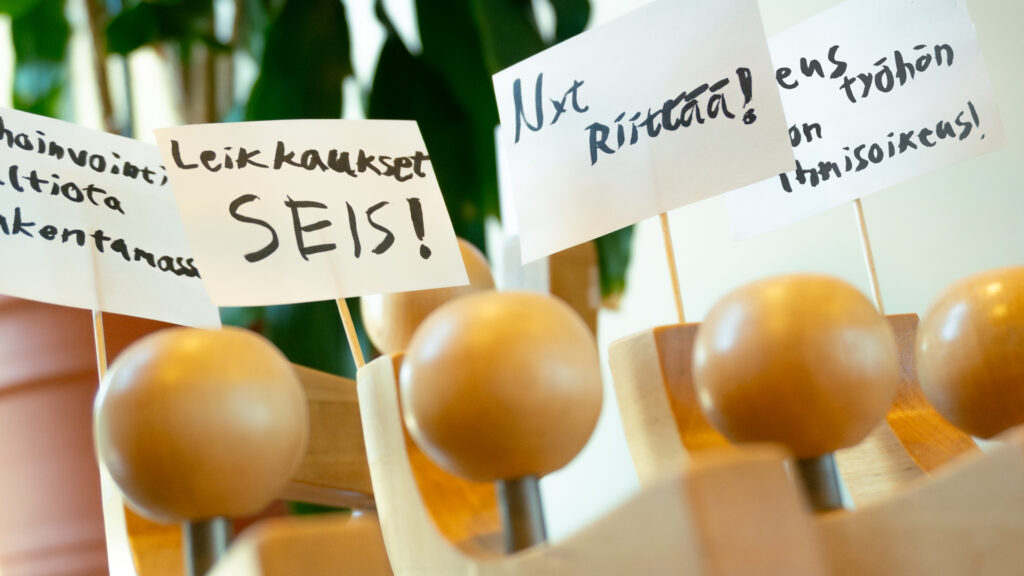 Puiset Vatesukkelit mielenosoituksessa kera kyltein, joissa lukee 'Nyt riittää!' 'Leikkaukset seis'